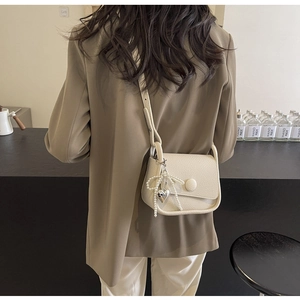 Detail of cream lychee texture saddle bag featuring pearl and heart charm accents