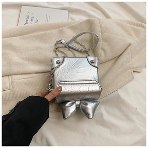 Detailed view of silver bow-knot box bag with metallic crinkled texture and chain strap