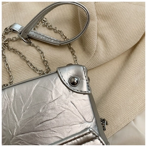 Close-up of silver mini box bag featuring crinkled texture and metallic chain strap