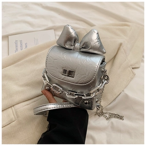 Close-up of a silver mini box bag featuring a large bow and textured metallic finish