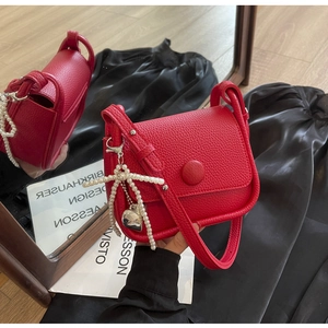 Detail of red lychee grain saddle bag featuring pearl bow and heart metal charm