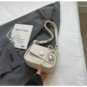 Detail of cream white lychee grain saddle bag with pearl bow chain and heart charm