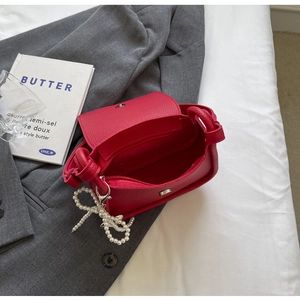 Close-up of red lychee grain saddle bag interior showing zipper pocket and pearl bow