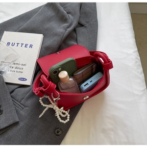 Internal capacity of the red lychee leather saddle bag with pearl bow and daily essentials