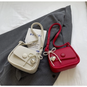 Close-up of pebble leather texture on saddle bags with pearl bow and silver heart charms