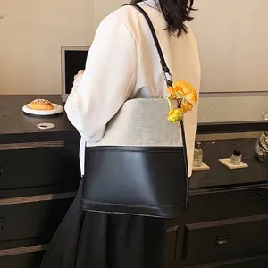 Fashionable beige canvas and black leather bucket bag with a yellow flower detail