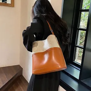 Canvas and brown leather bucket bag shown on model with shoulder strap design