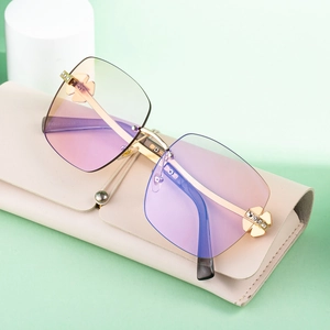 Frameless gradient sunglasses with gold clover diamond accents on beige leather case
