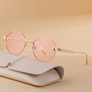 Octagon metal sunglasses with pink tinted lenses and a gold frame on a leather case