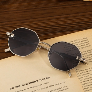 Octagonal silver metal sunglasses with dark grey lenses on vintage paper background