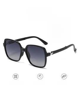 Detail of metal hinge on oversized black folding sunglasses with gradient lenses