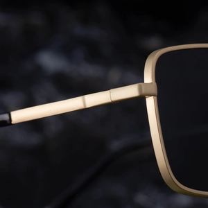 Detail of matte gold metal hinges and square frame edges on premium sunglasses