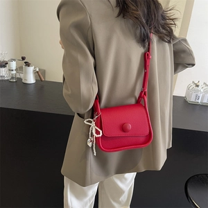 Chic red litchi texture saddle bag with pearl bow charm and decorative round buckle