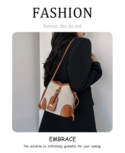 Detail of canvas bucket bag with brown leather trim and drawstring closure on a model