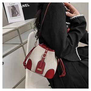Close-up of contrast bucket bag with cream canvas, burgundy leather, and gold hardware