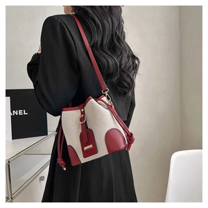 Detail view of a vintage drawstring bucket bag in beige canvas and red leather trim