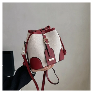 Detail of retro bucket bag with cream woven fabric and deep red leather accents