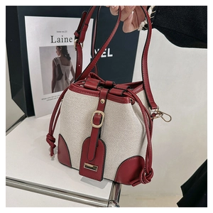 Detail of woven bucket bag with red leather trim and adjustable shoulder strap