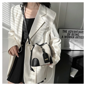 Detail of canvas bucket bag with black leather trim and strap shown on model's shoulder