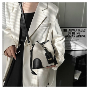 Detail of cream canvas bucket bag with black leather trim and chic drawstring closure