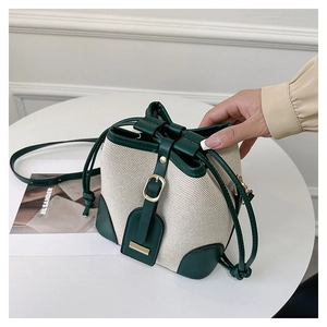 Detail of retro color-block bucket bag with green leather trim and beige canvas texture