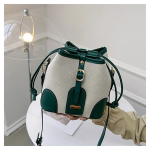 Close-up of canvas bucket bag with green leather trim and golden buckle detail
