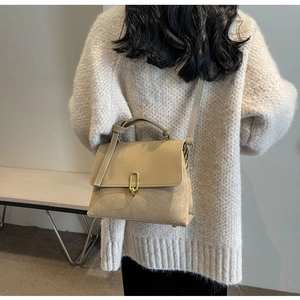 Beige crossbody bag worn by model in a soft knit sweater for a modern urban look