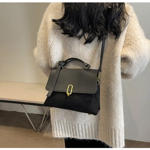 Detail of a chic black textured leather handbag featuring a gold U-shaped metal buckle