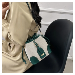 Detail of vintage drawstring bucket bag in beige canvas and green leather on model