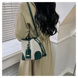 Detail of retro canvas bucket bag with green leather trim and golden metal buckle