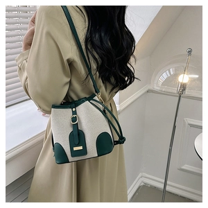 Detail of vintage canvas and green leather bucket bag on a model in soft window light