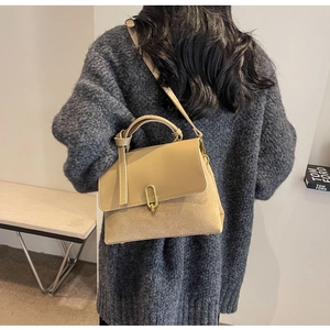 Detail view of khaki patchwork handbag with gold metal clasp on model back