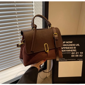 Detailed close-up of retro leather handbag with suede patchwork and gold buckle