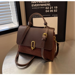 Detail of caramel brown handbag featuring gold U-shaped lock and premium suede texture