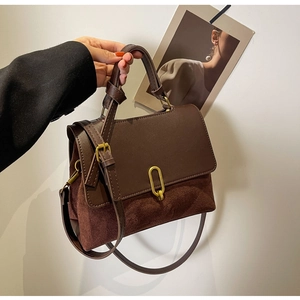 Detail view of brown vintage handbag featuring mixed textures and gold oval metal clasp