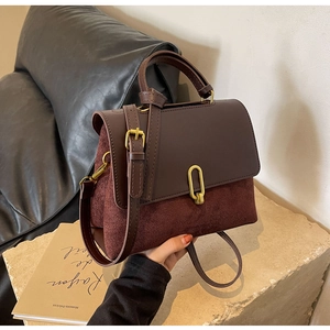 Detail of vintage tote bag featuring brown leather and burgundy suede textures on a stone surface