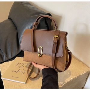 Detailed close-up of brown leather bag with golden U-shaped clasp and mixed texture finish