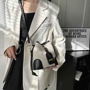 Vintage canvas and leather bucket bag for women with stylish metal buckle on white suit