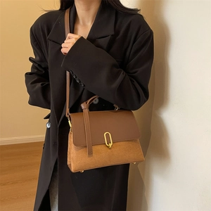Retro brown contrast shoulder bag with golden oval buckle worn by model in black suit