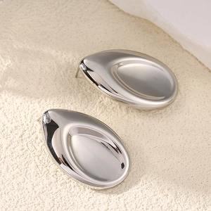 Detailed view of silver teardrop stud earrings on a minimalist textured stone background