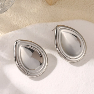 Macro detail of silver teardrop stud earrings with layered metallic design and high-polish finish