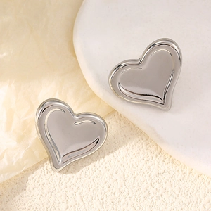 Detailed view of polished silver heart-shaped stud earrings on a ceramic display tray