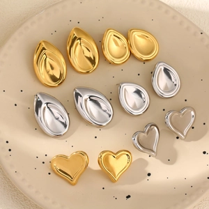 Water drop and heart stud earrings in gold and silver finish on a ceramic plate