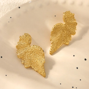 Vue macro de boucles d'oreilles feuilles dorées 18 carats avec texture nervurée détaillée