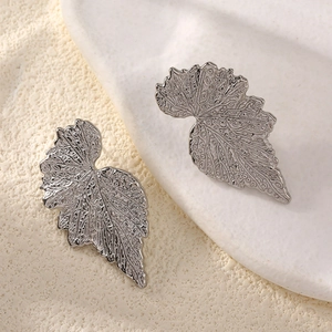 Gros plan de boucles d'oreilles feuille vintage argentée aux nervures détaillées