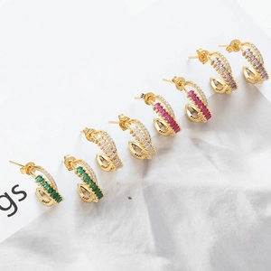 Detail of C-shaped gold earrings set with double-row emerald and zircon stones