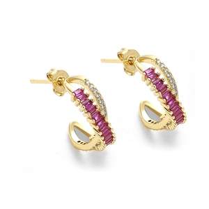 Macro detail of C-shaped copper earrings with red crystals and white zircons