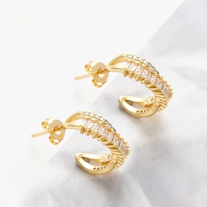 Detailed macro view of gold-plated C-shaped earrings with double-row cubic zirconia inlay