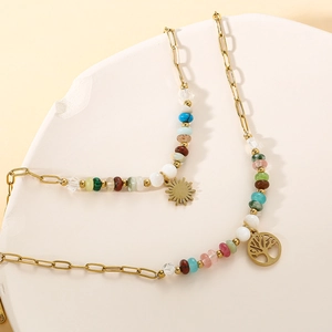 Golden Tree of Life bracelet with colorful beads and sun pendant on a white tray