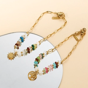 Detail of tree of life charm and colorful beaded stainless steel chain on a mirror surface